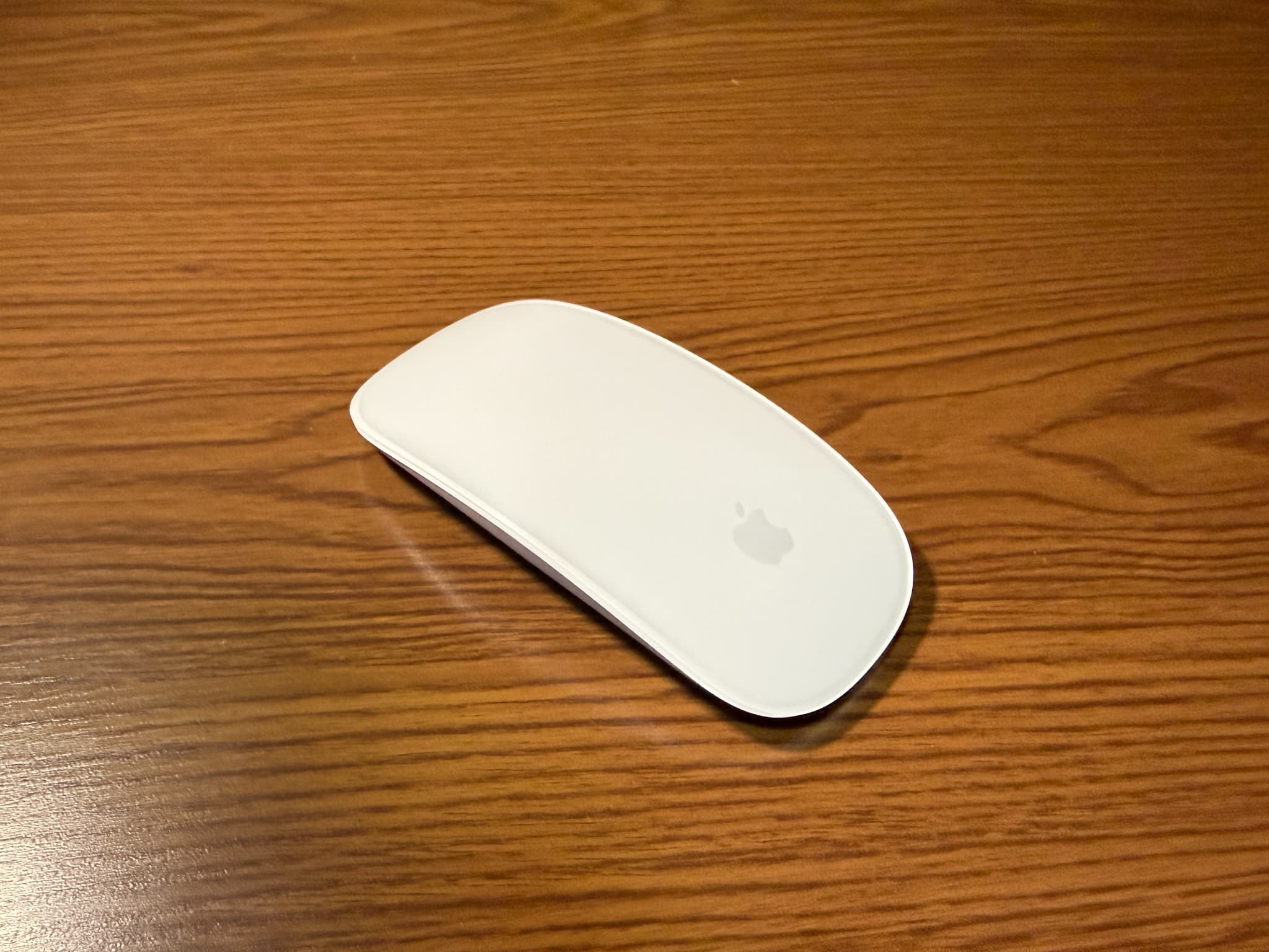 木のテーブルに置かれた白いアップル製マウス