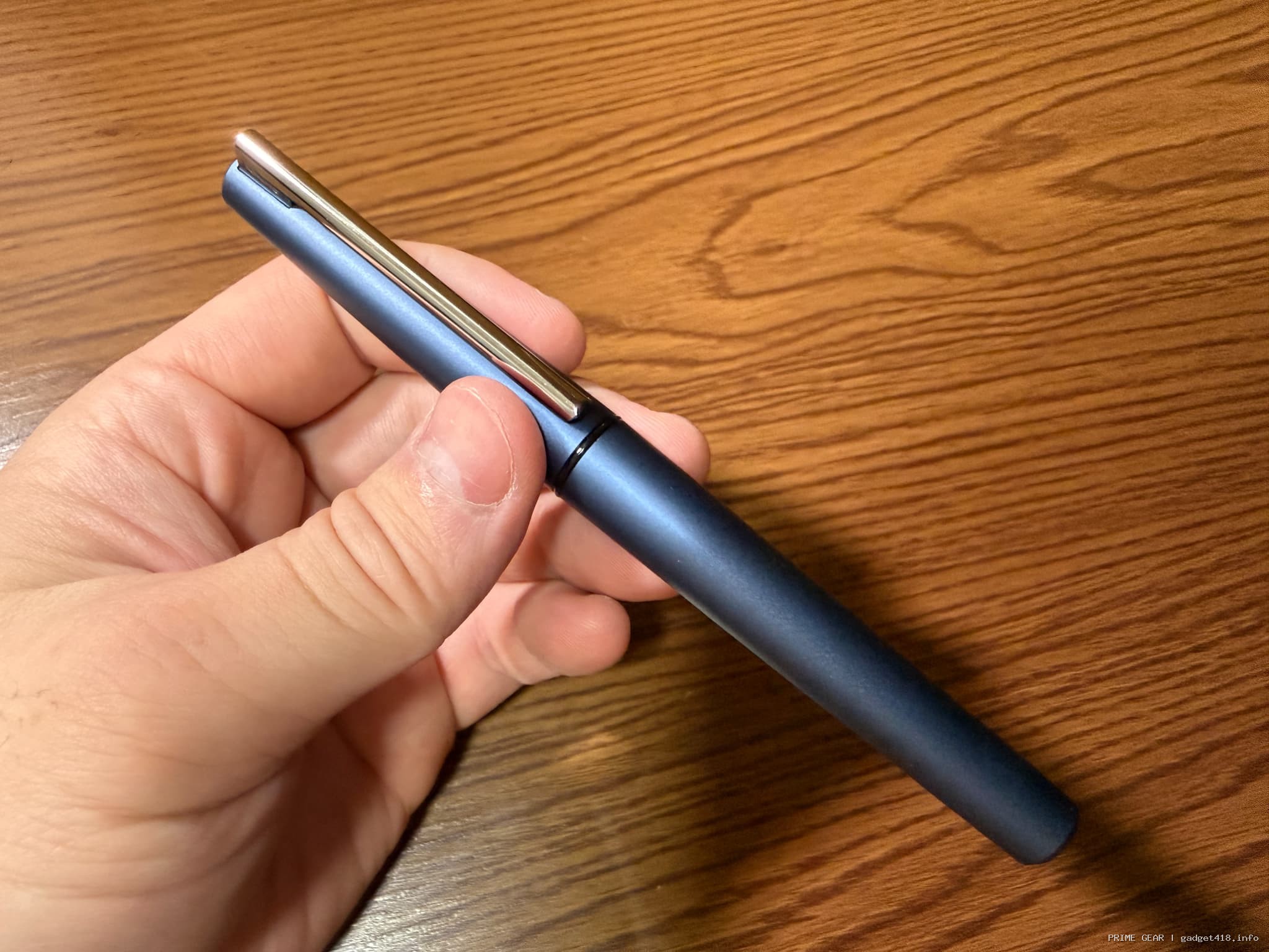 濃い青色のペンを持つ手と木目テーブル