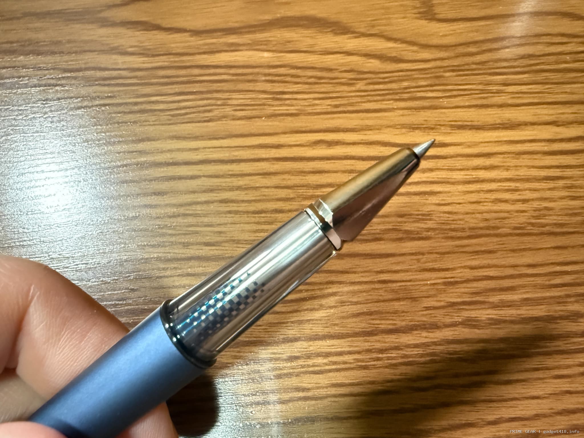 手に持つ青いボールペン 木目の背景