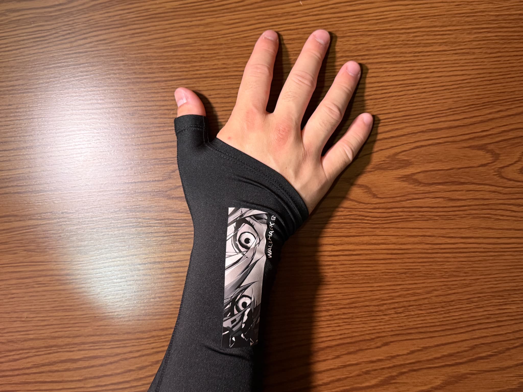 木製のテーブルに置かれた、漫画の絵柄が入った黒い手袋をはめた手