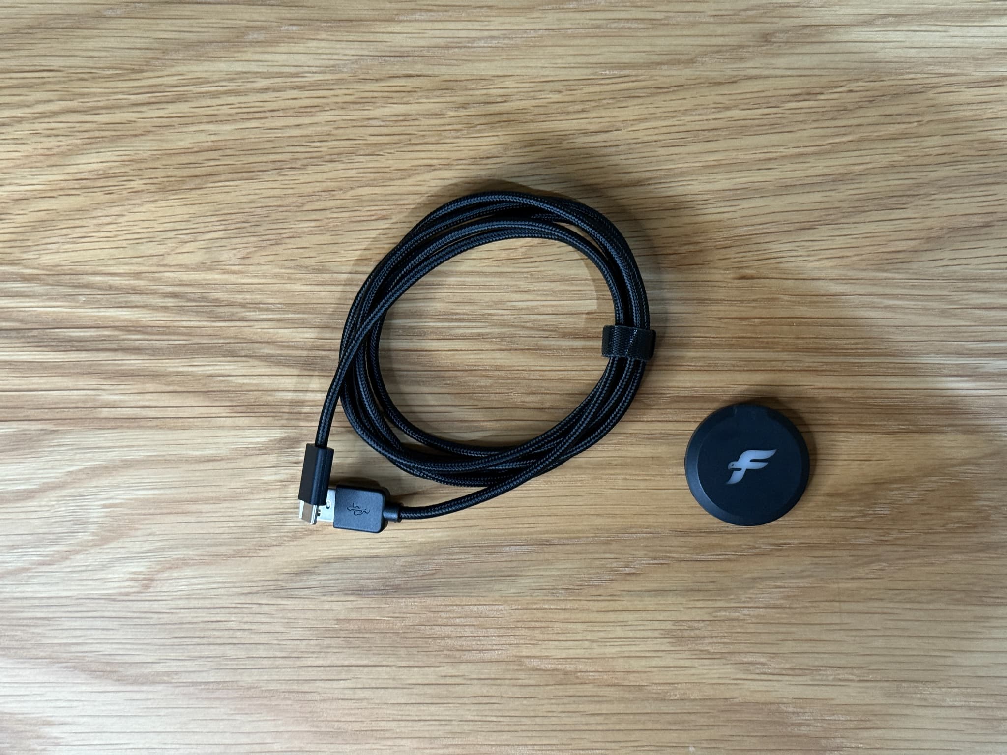 黒い充電ケーブルとロゴ入り円形小物